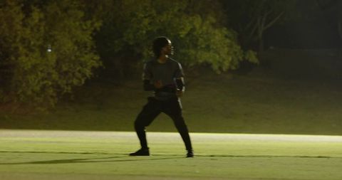 Diverse coach guiding athlete through sprint return drill on floodlit turf at night