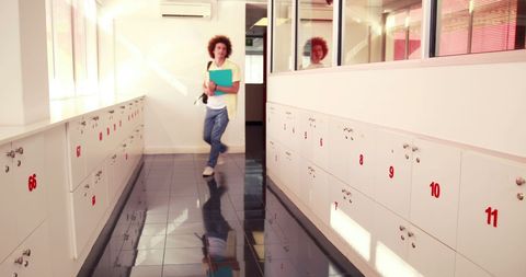 Professional female navigating bright corridor with reflections