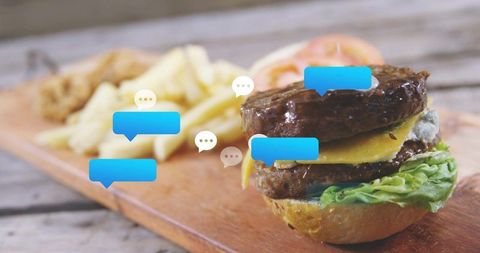 Double cheeseburger with fries on rustic wooden board with chat bubble overlay for review