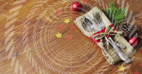 Festive holiday table with wrapped silverware, plaid ribbon, pinecones and evergreen accents