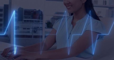 Asian professional typing at desk smiling with ecg waveform overlay for healthtech startup