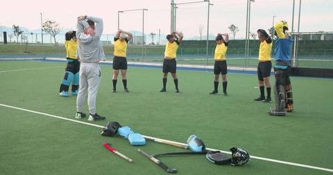Field Hockey Team in Stretching Routine on Turf