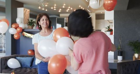 Senior Friends Decorating Home with Balloons for Birthday Celebration