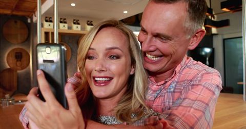 Happy middle-aged couple taking selfie indoors