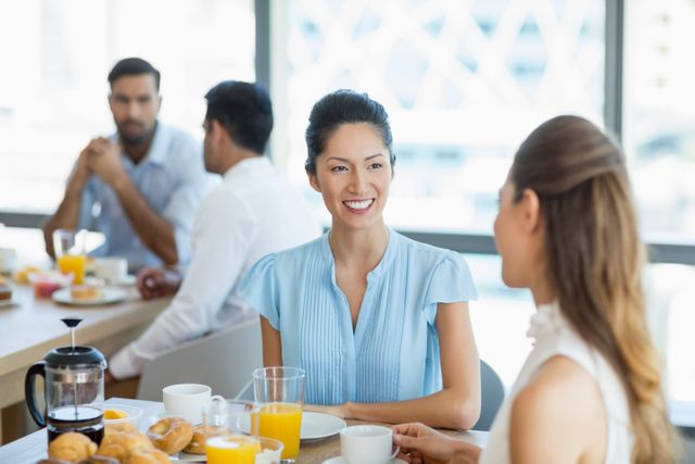 Smiling business colleagues having breakfast together in office cafeteria