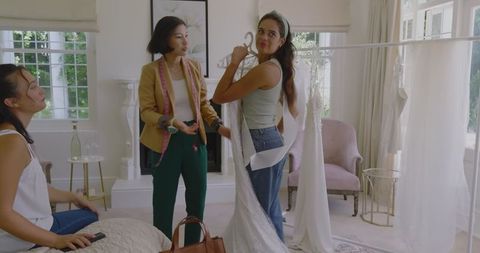 Bride-to-Be Excitedly Choosing Wedding Dress with Friends at Home