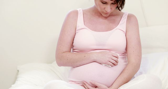 Serene Pregnant Woman Holding Belly on Comfortable Bed - Download Free Stock Images Pikwizard.com