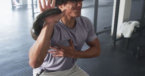 Man with curly hair concentrated kettlebell workout in gym