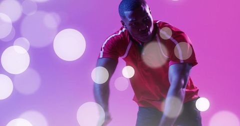 Athlete in Red Stretching Arms Amid Vibrant Studio Lights