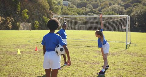 Diverse Female Children Practicing Soccer on Field with Blue Jerseys