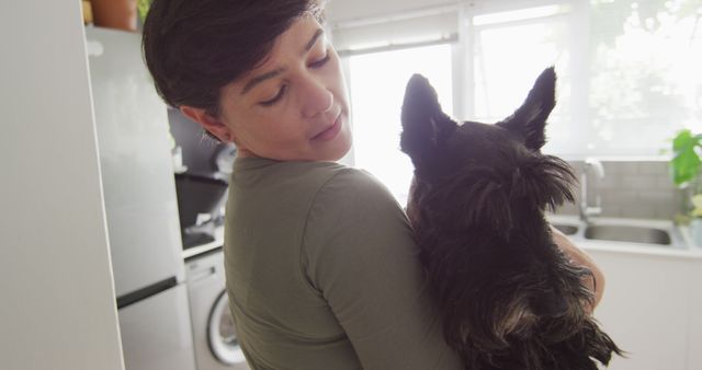 Caucasian woman holding her dog in the kitchen at home. pet love and care concept