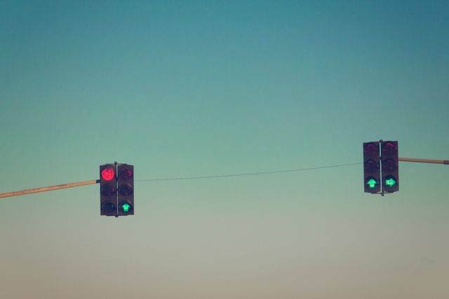 Traffic lights with go and stop signals against a clear sky backdrop are ideal for concepts involving road safety, transportation systems, city infrastructure, and urban planning. Suitable for blogs, articles, educational materials, and not for commercial adverts.