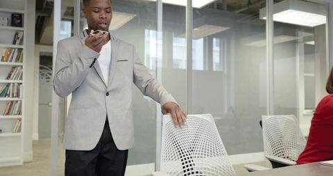Delivering presentation using smartphone in modern glass-walled conference room with white chair