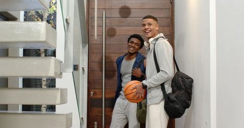 Energetic friends entering home with basketball in hand