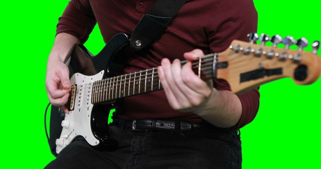 Close-up of a person playing an electric guitar against a green screen background. Can be used for music tutorials, promotional materials, or learning resources for guitar playing.