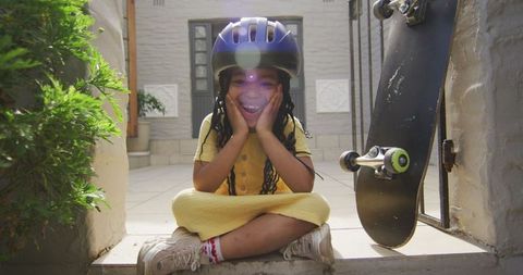Joyful Young Girl with Helmet Sitting Near Skateboard Outdoors