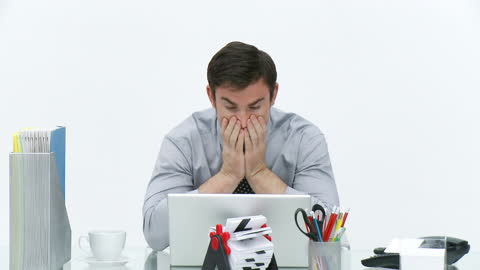 Frustrated Businessman at Office Desk with Laptop in Modern Workspace