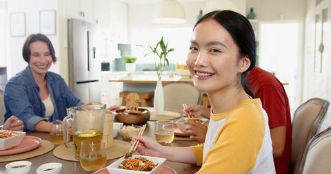 Asian Family Enjoying Meal Together Around Modern Kitchen Table