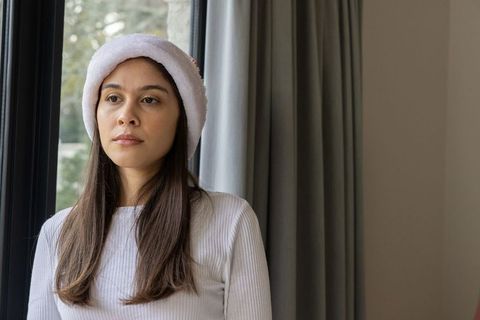 Woman wearing santa hat gazing out window during quiet holiday moment