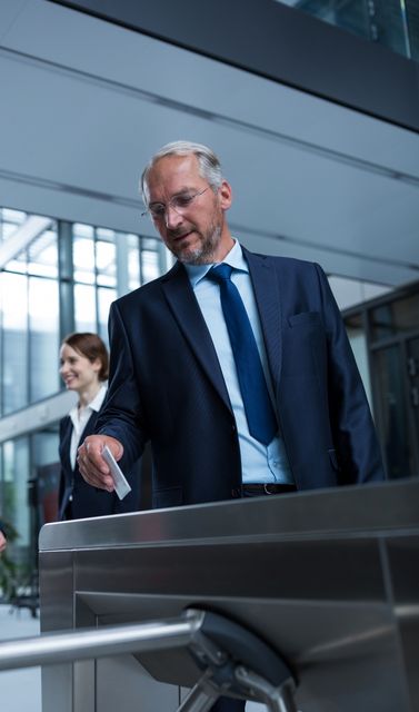 Businessman scanning his access card at a turnstile gate in a modern office building. Ideal for illustrating corporate security, access control systems, professional environments, and modern workplace technology.