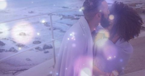 Romantic couple cuddling on seaside promenade at dusk with dreamy bokeh lights