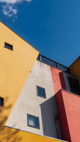 Tilting vertical video revealing colorful modern facades with geometric windows and shadows