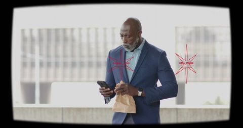 Executive checking smartphone while eating lunch on terrace, wearing navy suit and smartwatch