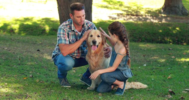 A Caucasian middle-aged man and a young girl are affectionately interacting with a golden retriever in a sunny park, with copy space. Their bonding moment with the pet highlights the importance of family time and the joy animals can bring into our lives.