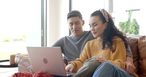 Couple Relaxing at Home on Couch Using a Laptop