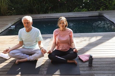 Serene Senior Couple Meditating on Poolside Deck