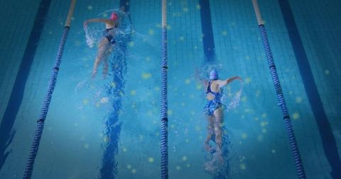 Two Women Swimming Freestyle Training in Indoor Pool Lanes with Dynamic Splash Motion