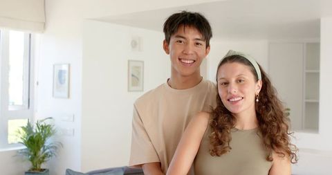 Smiling young couple standing in bright minimalist living room with neutral decor