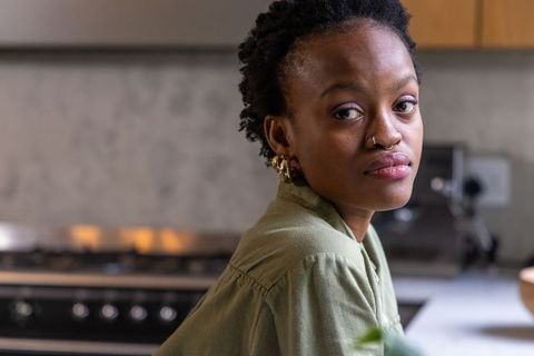 African american woman leaning in kitchen glancing over shoulder near stove