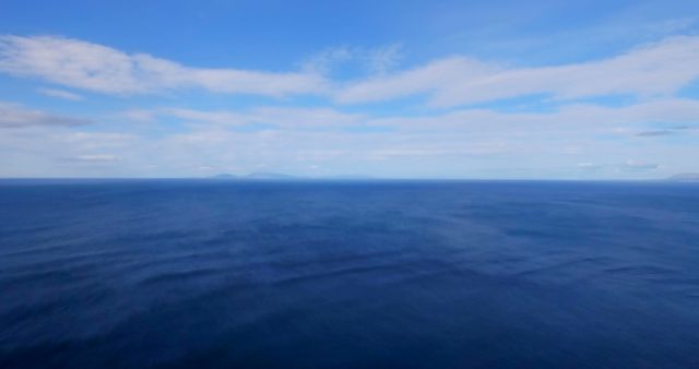 This image captures the vastness of the ocean under a clear, sunny sky. The tranquil blue waters stretch out to the horizon, giving a sense of infinity and calm. Ideal for travel brochures, nature websites, or relaxation and meditation content. Its serene atmosphere makes it suitable for backgrounds in apps or websites aimed at promoting well-being or leisure activities.