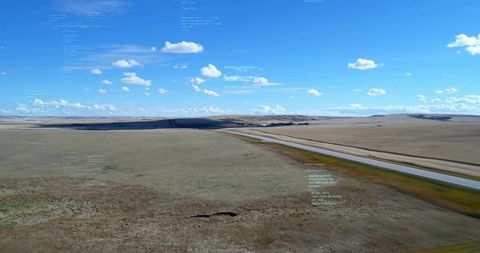 Aerial prairie highway stretching to horizon with open grassland, clouds and code overlay