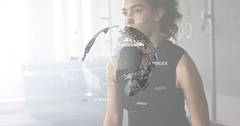 Woman focusing on holographic globe in minimalist gym for futuristic fitness technology