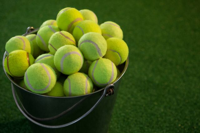 Tennis balls in bucket on field