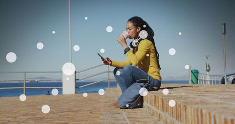 Young woman enjoying coffee break by the seaside promenade