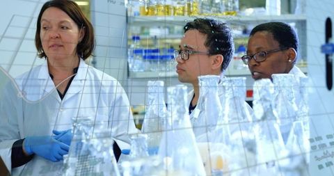 Laboratory team collaborating over glassware and data visualization for chemistry research