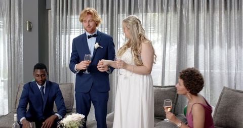 Multiracial friends toasting newlyweds at wedding reception