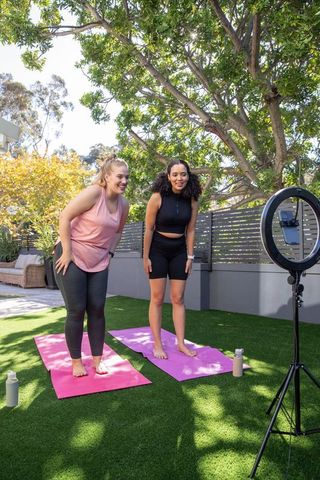Diverse Friends Stretching with Ring Light in Outdoor Yoga Session