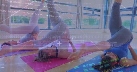 Group women practicing plow pose in yoga studio with digital stock market overlay