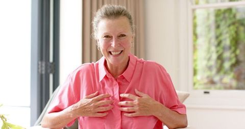 Happy Senior Woman in Pink Shirt Enjoying Moment Indoors