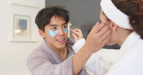 Couple applying blue hydrogel eye patches during cozy at-home spa and skincare moment