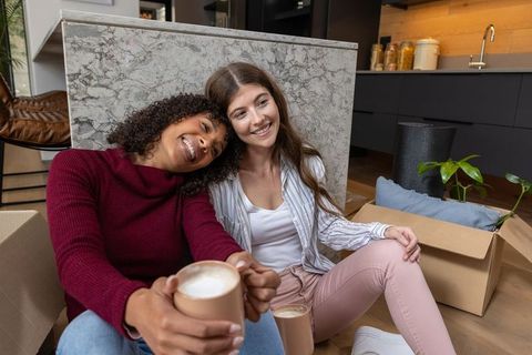 Diverse friends relaxing in new home with coffee and laughter