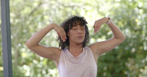Woman raising arms and closing eyes while tracking wellness with smartwatch outdoors
