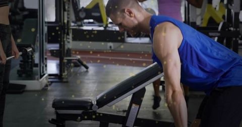 Man leaning and adjusting incline bench in gym preparing for dumbbell row workout