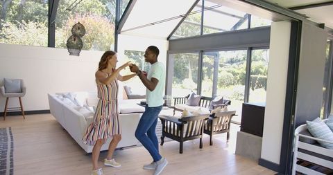Couple Joyfully Dancing in Modern Living Room with Big Windows