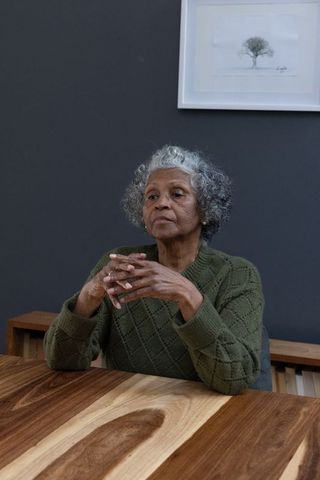 Senior Woman Contemplating at Modern Wooden Table