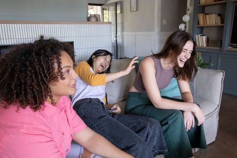 Diverse Female Friends Laughing on Couch Socializing Together